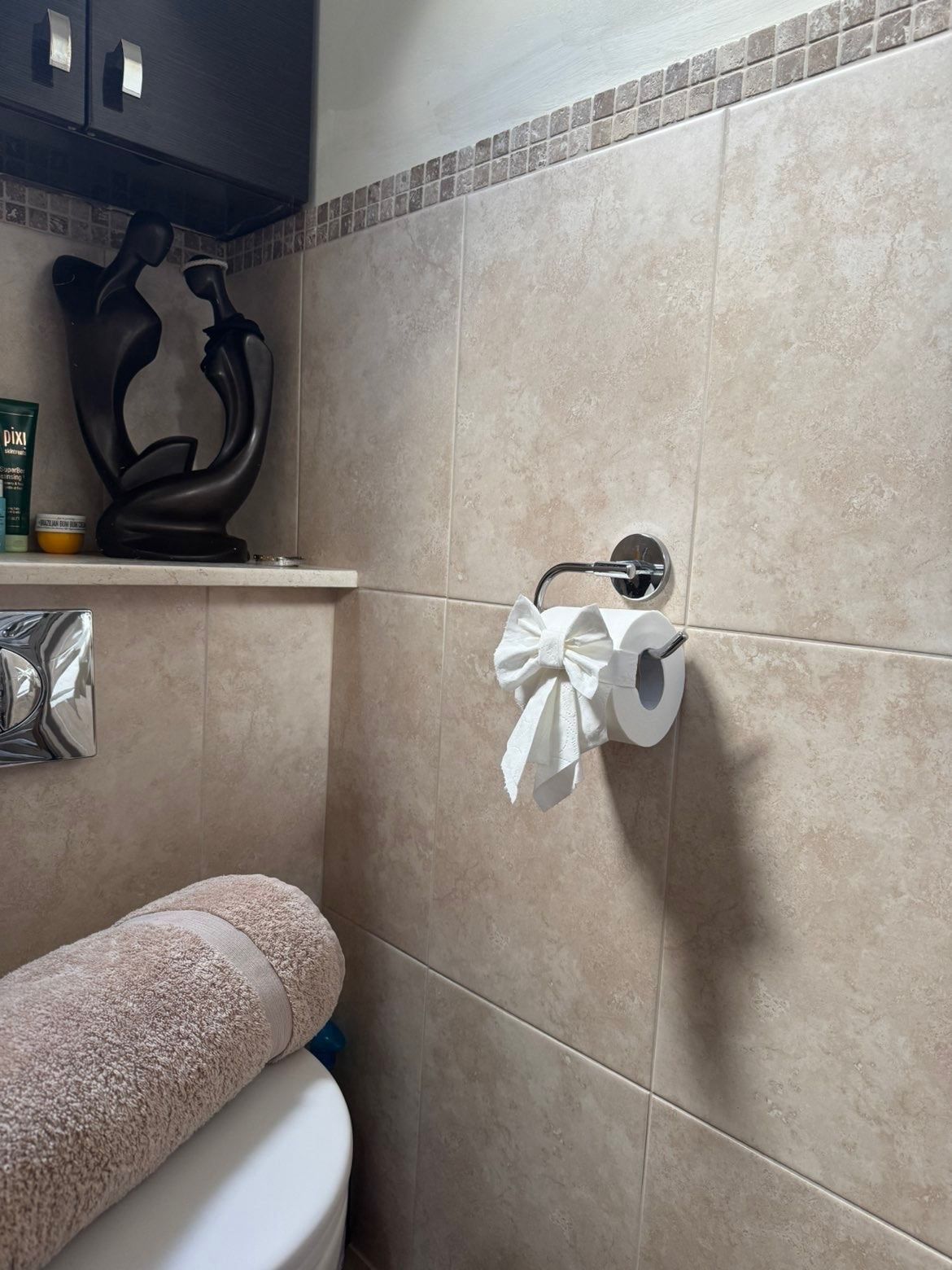 Close view of polished chrome fittings and clean tiles in a bathroom