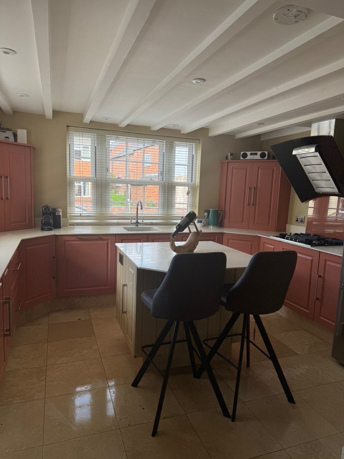 Bright, freshly cleaned kitchen with island, bar stools and a gleaming tiled floor